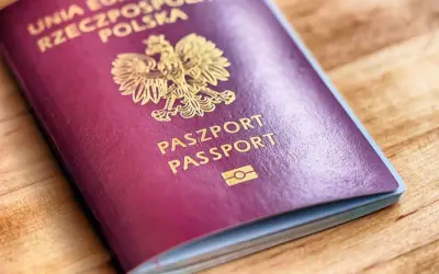 Ciemnoczerwony paszport biometryczny Rzeczypospolitej Polskiej z godłem i napisem "PASZPORT PASSPORT" na drewnianym tle.