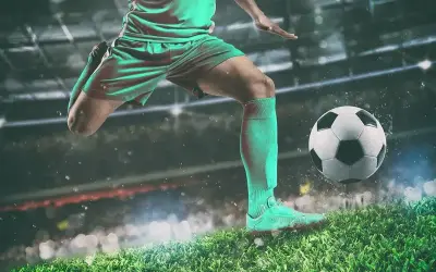 Piłkarz w akcji, jak legenda futbolu, kopie piłkę na tle stadionu.