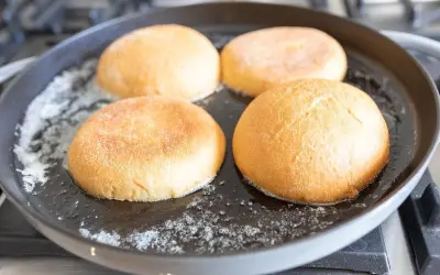Cztery bułki do burgerów podsmażane na patelni z masłem.