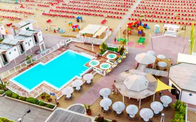 Vista aerea del lido delle sirene Cattolica: piscina, vasche idromassaggio, lettini rossi e ombrelloni sulla spiaggia.