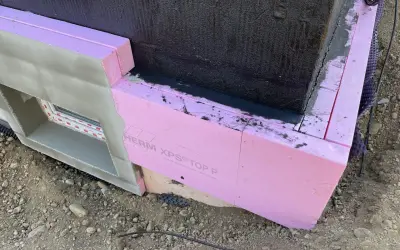 Dämmung wird angebracht. Pinke Styrodurplatten werden sorgfältig an die Wand geklebt, um das Gebäude zu isolieren.