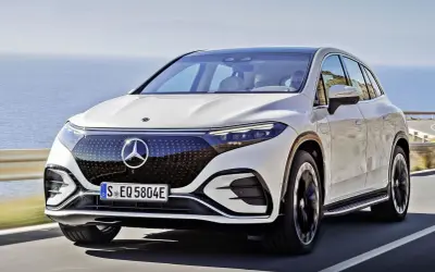 Biały Mercedes EQS SUV jedzie wzdłuż malowniczego wybrzeża.