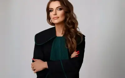 Kobieta w todze prawniczej, z rękami skrzyżowanymi na piersi, na jasnym tle.