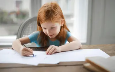 Ruda dziewczynka rysuje. Jej skupienie i zaangażowanie to cechy, które doceni każdy pedagog specjalny, posiadający odpowiednie kwalifikacje.