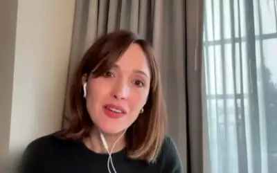 Rose Byrne w jednym ze swoich filmów, w białych słuchawkach, z uśmiechem na twarzy.