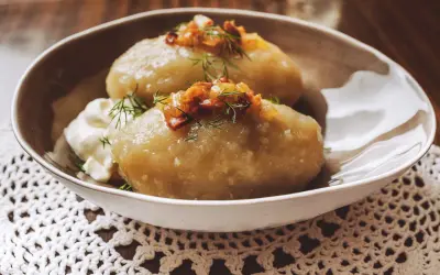 Cepelinai, comida típica de Lituania, servidos con crema agria y tocino crujiente.