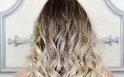 Piękne, falowane włosy z efektem ombre blond, przechodzące od ciemnego brązu do jasnego blondu.