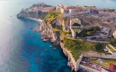 Fortificazioni storiche su una scogliera a picco sul mare turchese, un gioiello delle città della Toscana.
