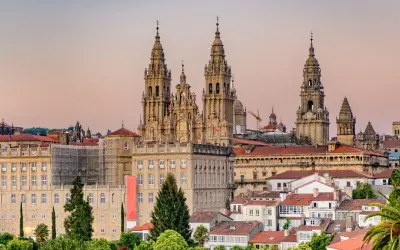Majestatyczna katedra w Santiago de Compostela góruje nad miastem. W tle widać budynki i palmy.
