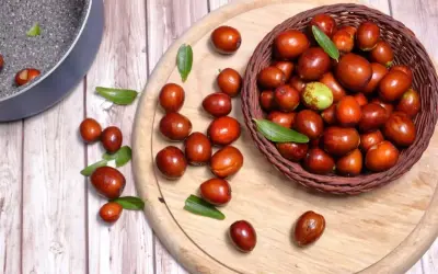 Giuggiole rosse e verdi in un cesto e sparse su un tagliere. Scopri quante calorie hanno le giuggiole per uno snack salutare.