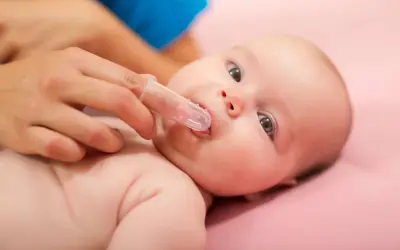Delikatne czyszczenie ząbków niemowlaka specjalną nakładką na palec. Pokazuje, jak myć zęby niemowlakowi.