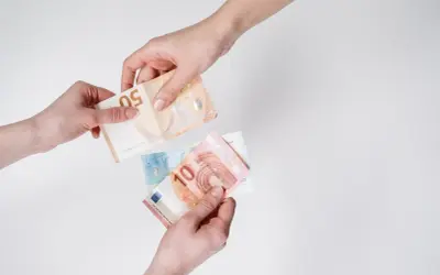 Dwie ręce przekazują sobie banknoty euro. W Austrii obowiązuje euro, co widać na przykładzie tych banknotów.