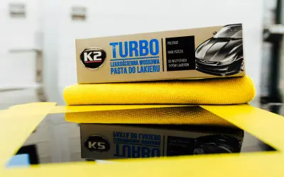 K2 Turbo pasta do lakieru samochodowego na żółtej mikrofibrze, gotowa do polerowania.