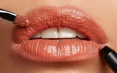 Labbra perfette con un tocco di colore. Un pennello applica un prodotto cremoso, mentre un rossetto definisce il contorno.