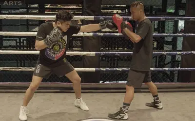 A boxer throws a jab punch during training in a boxing ring.