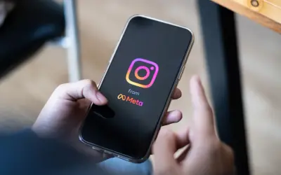 Dłoń trzyma smartfon z logo Instagrama i Meta. Zastanawiasz się, ile zarabiają polscy influencerzy za jeden post sponsorowany?