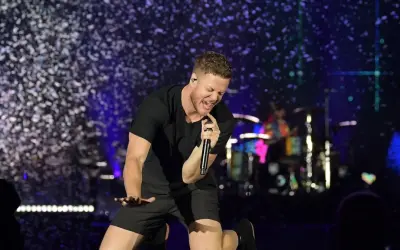Imagine Dragons wokalista Dan Reynolds śpiewa z pasją na scenie, otoczony konfetti.