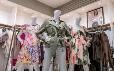 Manekiny w sukienkach w kwiaty i zielonej kurtce. To styl marki Scotch & Soda, znanej z kolorowych, letnich ubrań.