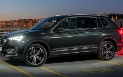 Ciemnozielony SUV, jeden z najbardziej polecanych samochodów 7-osobowych, zaparkowany na dachu parkingu nocą.