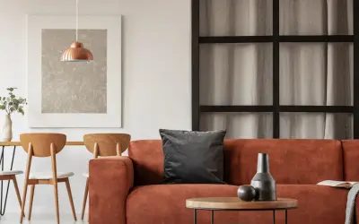Gemütliche Wohnung inspo: Orange Couch, Holztisch mit Stühlen und ein kupferfarbener Lampenschirm.