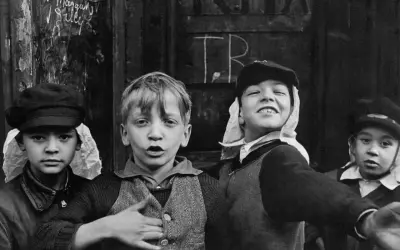 Bambini con cappelli, un'immagine che ricorda i grandi fotografi famosi, con un'espressione vivace e un gesto di invito.