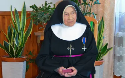 Siostra Antygony, w habicie i z krzyżem, siedzi wśród roślin. Może to być rozwiązanie krzyżówki z jej udziałem.