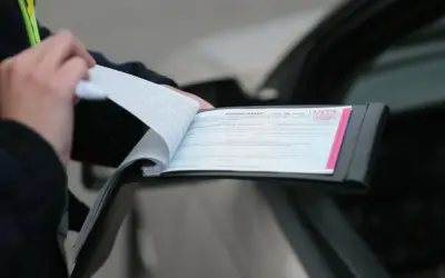 Policjant spisuje mandat karny po stłuczce. Dokument zawiera numer 1934776.