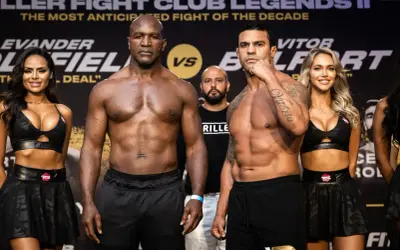 Evander Holyfield och Vitor Belfort står redo för en episk match. Ringflickor flankerar de muskulösa boxarna.
