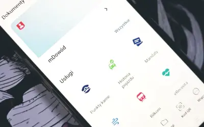 Na ekranie telefonu widać aplikację z opcjami: mDowód, Usługi, Punkty karne, Historia pojazdu, Mandaty. Możesz tu sprawdzić mandaty.