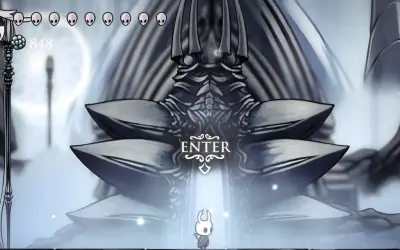 Mały rycerz stoi przed monumentalną bramą w White Palace Hollow Knight.
