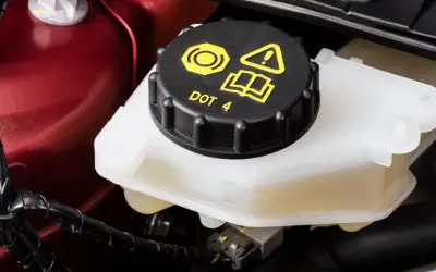 Réservoir de liquide de frein DOT 4, le niveau est visible sur le côté du récipient blanc.