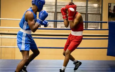Two boxers in a ring, one in blue, the other in red, showcasing the disciplined footwork and defensive stance characteristic of the cuban boxing style.