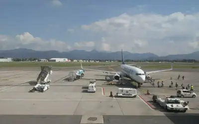 Samolot Ryanair na płycie lotniska Bergamo. W tle góry i budynki lotniskowe.