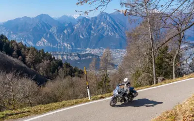 Motociclista in esplorazione dei punti panoramici del Lago di Garda, con montagne imponenti e un lago azzurro sullo sfondo.