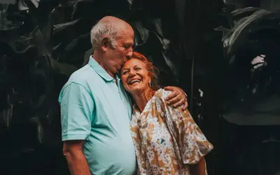 Un couple âgé s'embrasse tendrement, un moment de joie pour fêter sa retraite en famille.