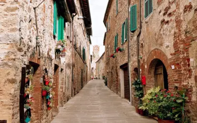 Un vicolo fiorito a Campagnatico, con case in pietra e persiane verdi. Un luogo incantevole da scoprire, tra scorci pittoreschi e storia.