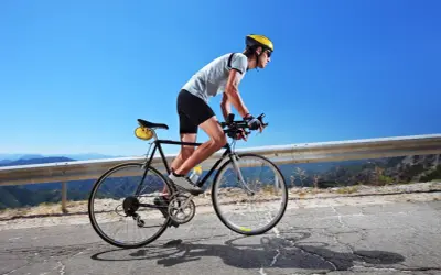 Kolarz w kasku i okularach pokonuje górską trasę. Czy 100 km na rowerze to dużo? Dla niego to wyzwanie!