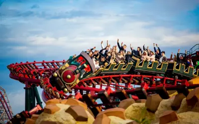 Energylandia pociąg z pasażerami wznosi się na torach kolejki górskiej, wszyscy krzyczą z radości.