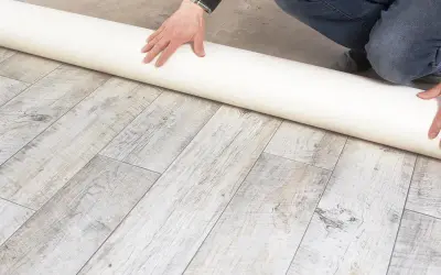 Eine Rolle Unterlage liegt auf einem Holzboden. Sie ist ideal, wenn Sie sich fragen, was kommt unter PVC Boden.