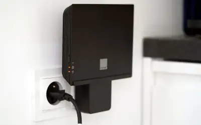 Czarny router Orange, model funbox 6, podłączony do gniazdka elektrycznego.