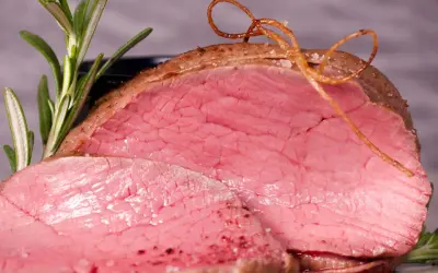 Saftiges Rinderfilet im Backofen, perfekt rosa gebraten, mit Rosmarin und einer dekorativen Schnur aus Bratensaft.