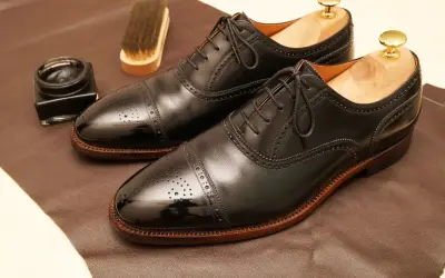 Paire de richelieus noirs brillants, prêts pour un glacage chaussure parfait. Pot de cirage et brosse à proximité.
