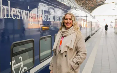Frau am Bahnsteig in Schleswig-Holstein, bereit für neue Abenteuer. Hier sind einige Flensburg Tipps für deine Reise!