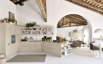 Jasna kuchnia shabby chic z drewnianymi belkami na suficie, wyspą i otwartą przestrzenią z sofą.