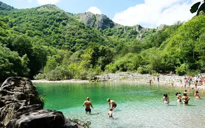 Gente disfrutando del agua cristalina en la olla de San Vicente, rodeada de exuberante vegetación y montañas.
