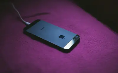 iPhone podłączony do ładowania. Dowiedz się, jak zmierzyć pojemność baterii, aby wiedzieć, jak długo telefon będzie działał.