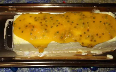 Gâteau glacé rectangulaire nappé d'un confit mangue passion aux graines visibles, sur un plateau doré.