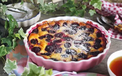 Un délicieux clafoutis aux prunes, saupoudré de sucre glace, prêt à être dégusté.