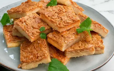 En hög med fyrkantiga bitar av mandelkaka, perfekt för att baka i långpanna. Garnerade med färska myntablad.