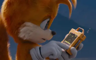 Tails Sonic, z dwoma ogonami, analizuje dane na żółtym urządzeniu.